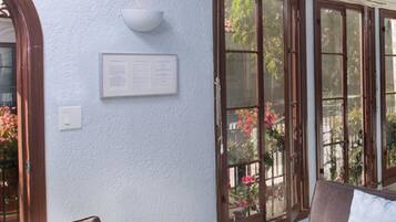 A room with a large window, a wall-mounted light fixture, and a framed notice.