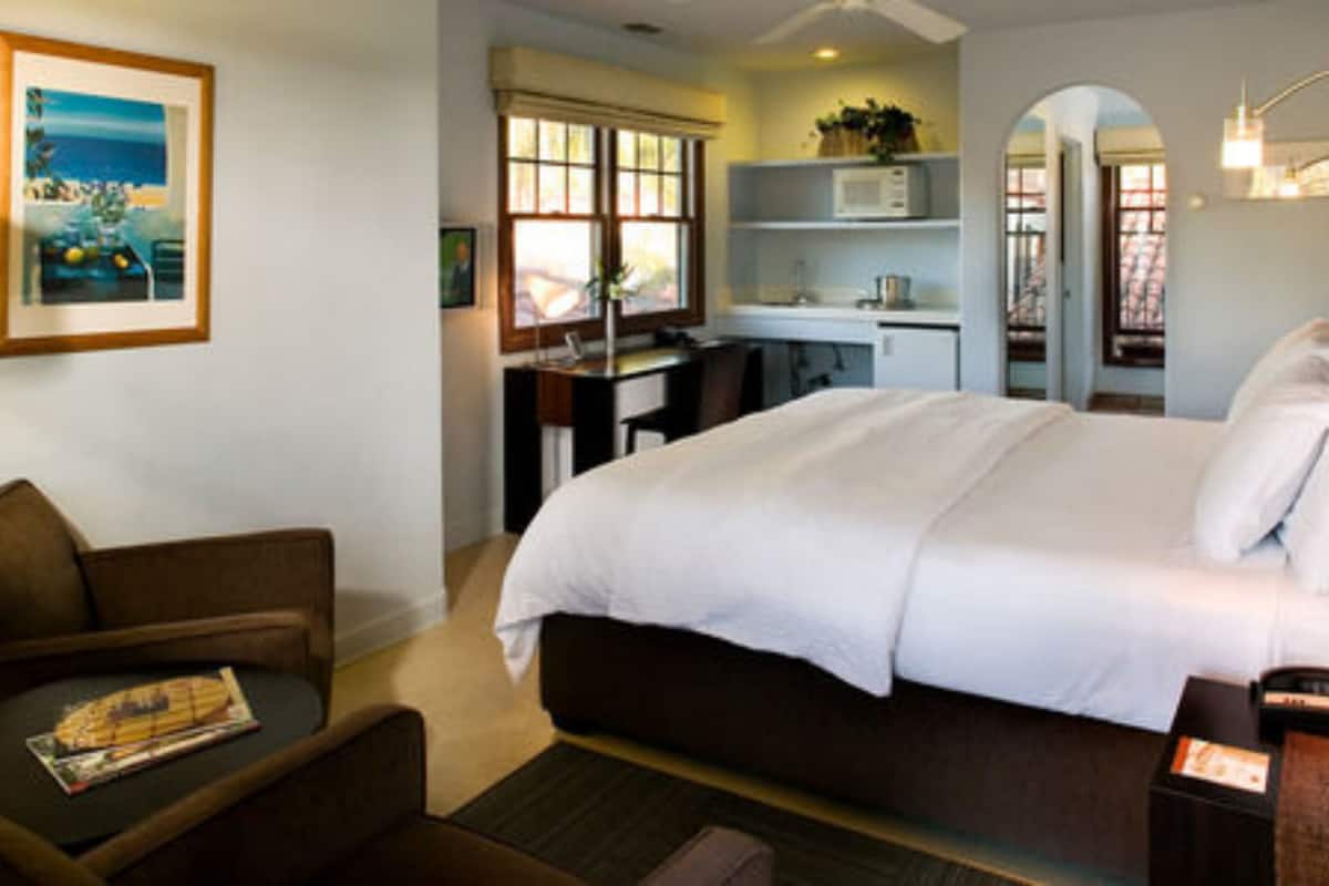 A hotel room with a large bed, a desk, a chair, and a small table.