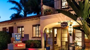 A hotel with a Mediterranean architectural style, featuring a balcony with potted plants, a well-lit entrance, and a sign indicating it is a Casa Del Mar Inn. - Casa Del Mar Inn (Santa Barbara)