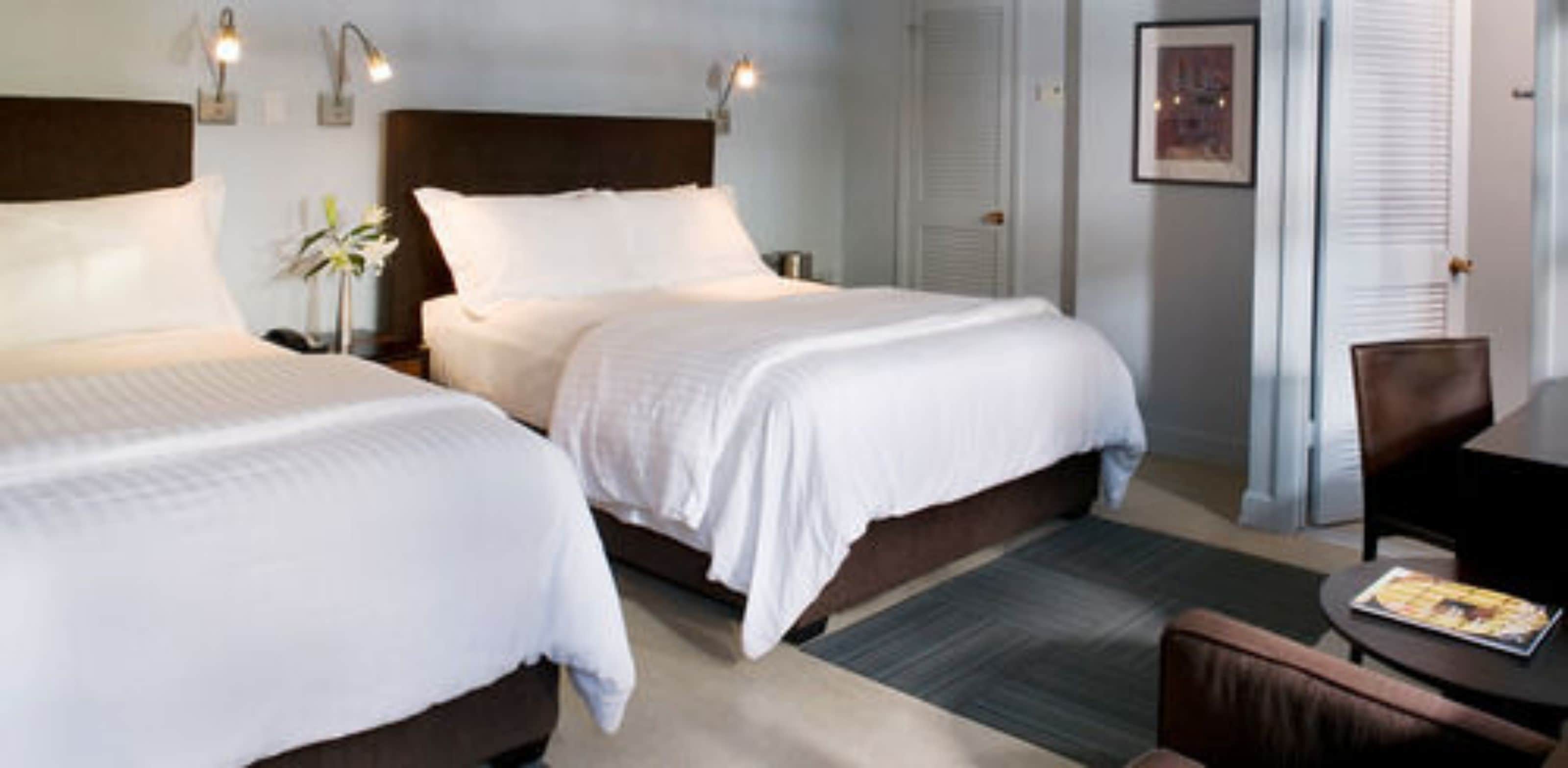 Une chambre d’hôtel avec deux lits, un bureau et une chaise.