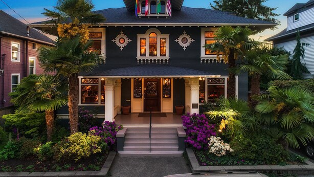 A Victorian-style building with a dark facade, ornate windows, and a balcony with flags. - Seattle Gaslight Inn (Seattle)