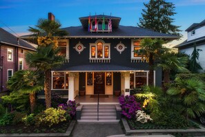 A Victorian-style building with a dark facade, ornate windows, and a balcony with flags. - Seattle Gaslight Inn (Seattle)