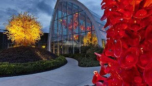 A modern building with a curved glass facade and a landscaped area with a sculptural tree and red glass elements. - Seattle Gaslight Inn (Seattle)