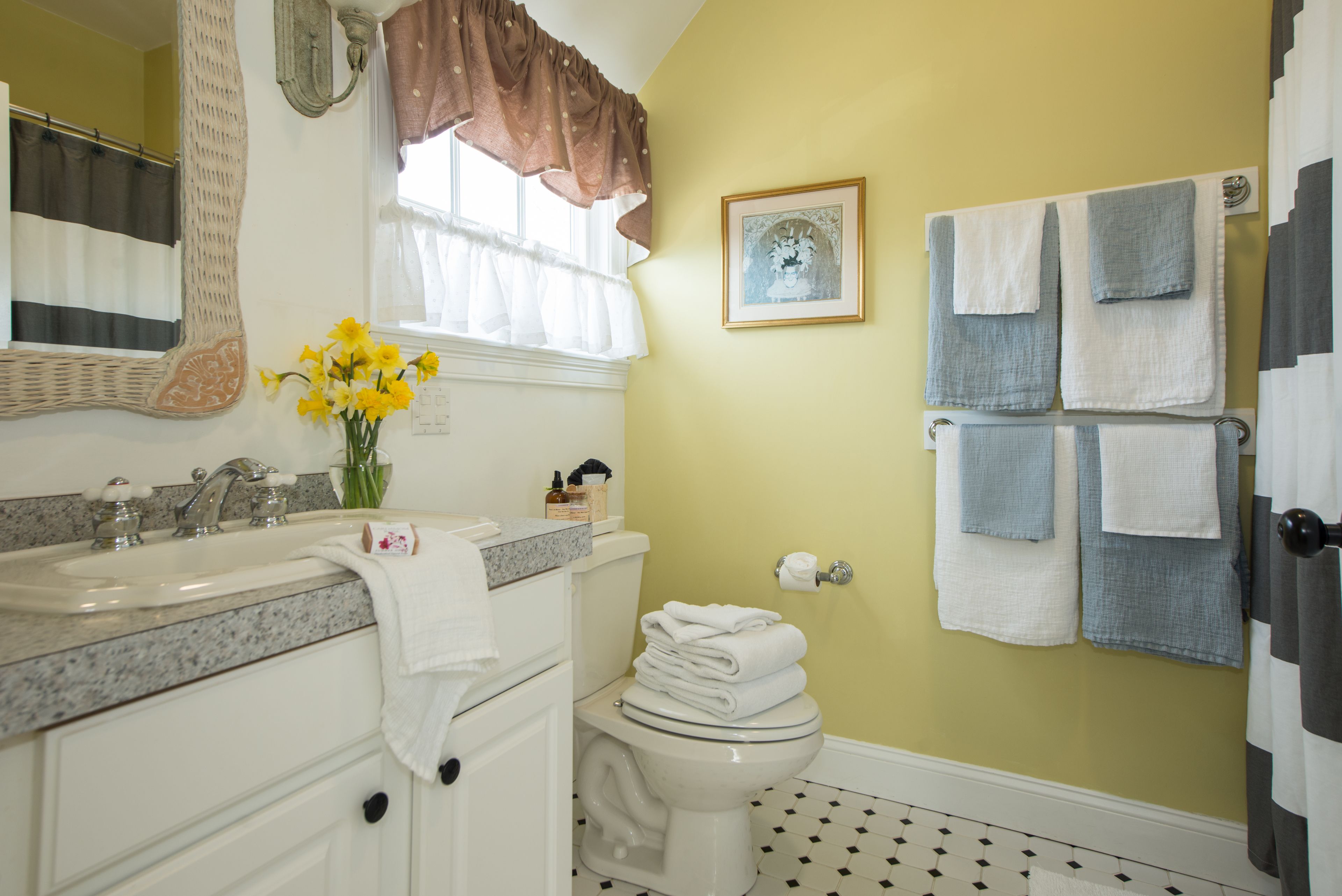 A bathroom with a sink, toilet, and a towel rack with multiple towels.