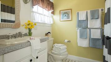 A bathroom with a sink, toilet, and a towel rack with multiple towels.