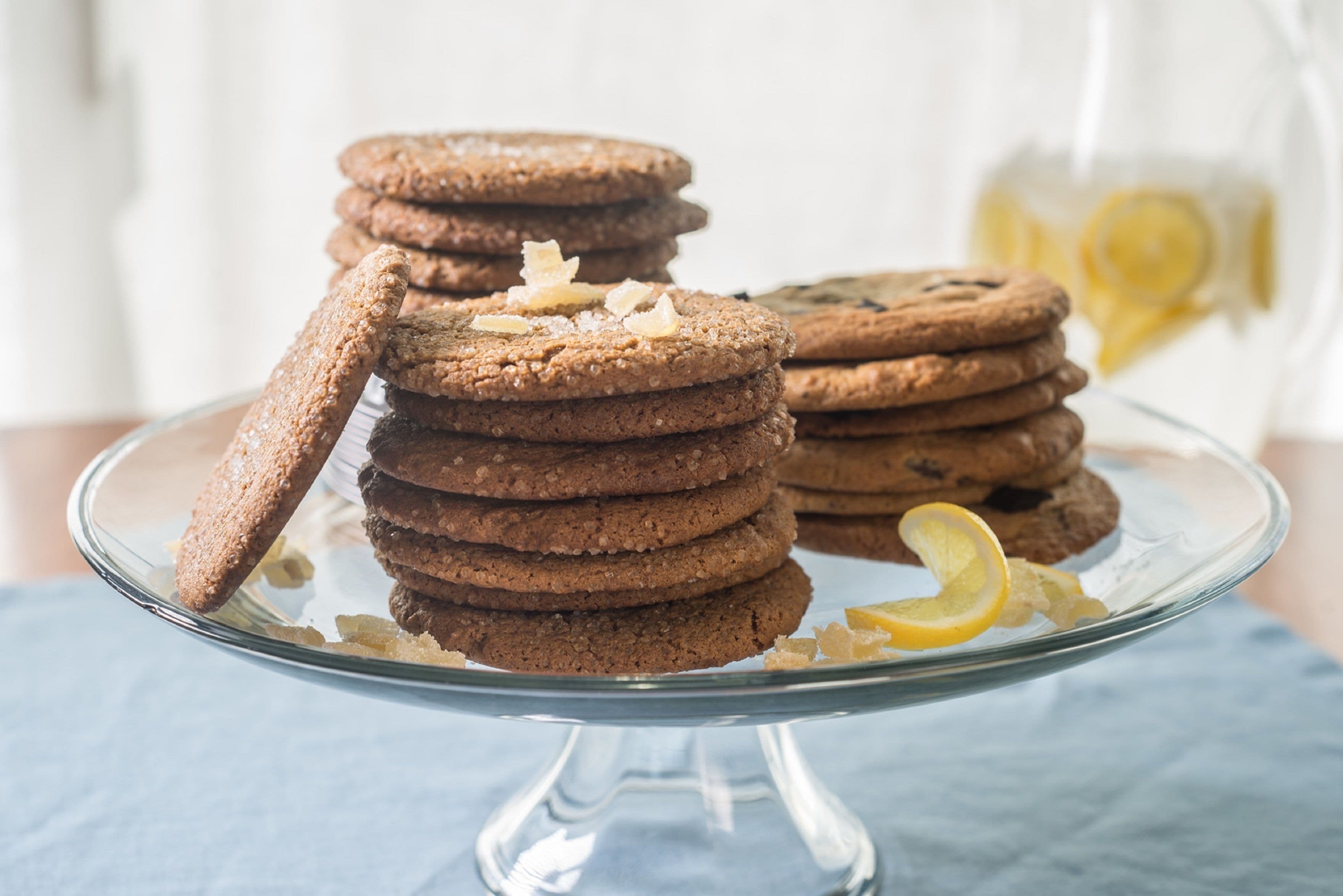 A stack of cookies on a glass plate with a lemon slice.
