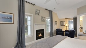 Un dormitorio con chimenea, dos sillones, una cama y vistas al exterior.