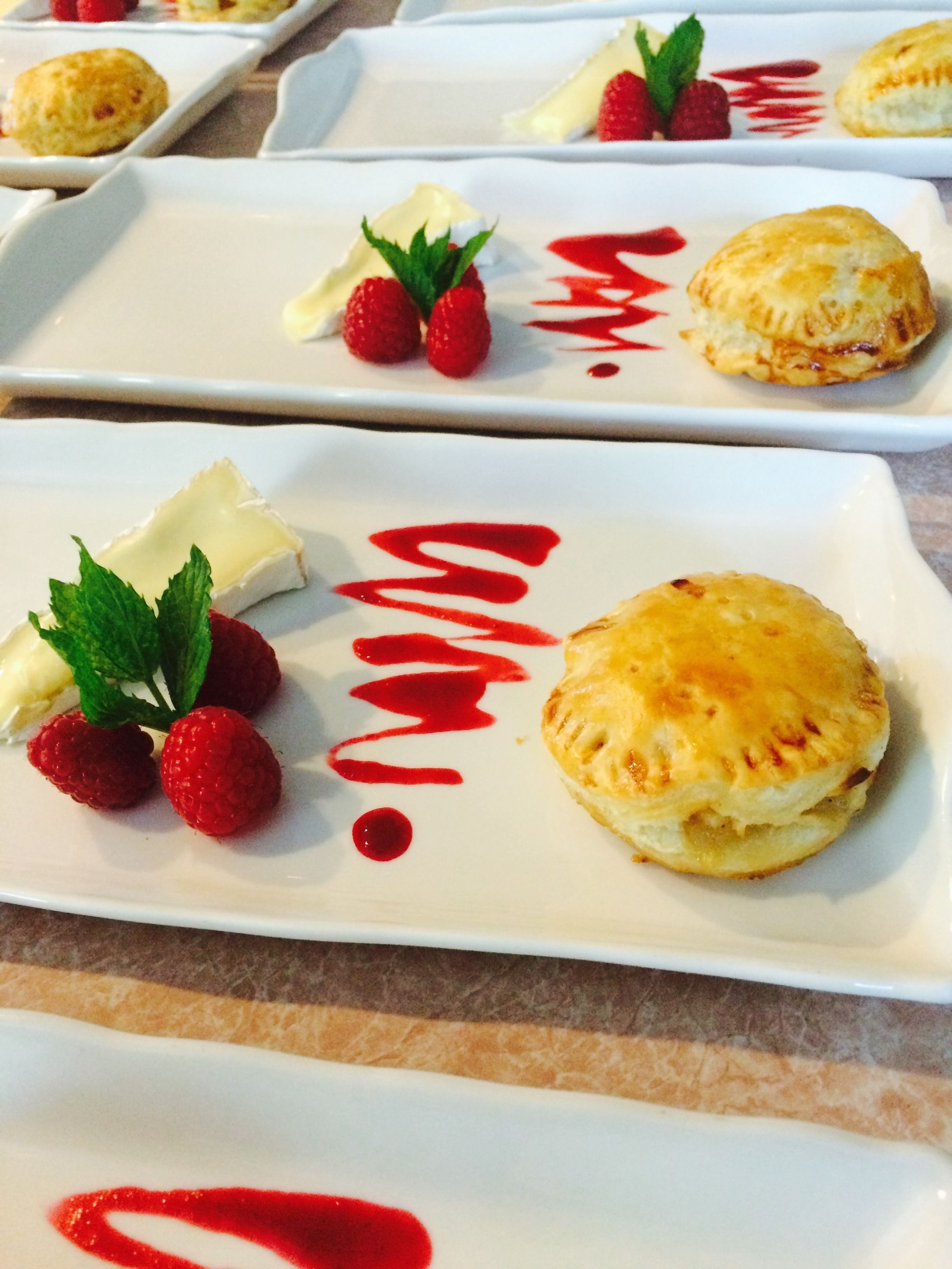 Un plato de postres con pastelería, fresas y salsa roja.