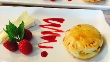 Un plato de postres con pastelería, fresas y salsa roja.