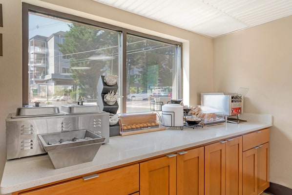 Una kitchenette con electrodomésticos de acero inoxidable, un expositor de pan y una cafetera.