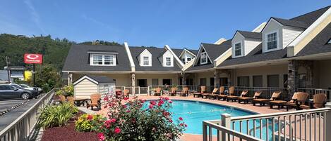 A hotel with a swimming pool, outdoor seating, and a view of a mountain.