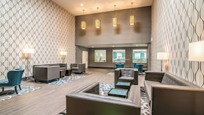 A lobby with patterned walls, leather seating, and pendant lighting.