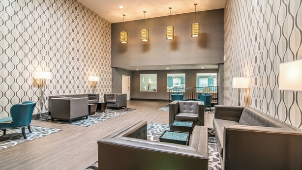 A lobby with patterned walls, leather seating, and pendant lighting. - Elevate Hotel at Sierra Blanca (Ruidoso)