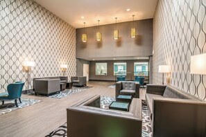 A lobby with patterned walls, leather seating, and pendant lighting.