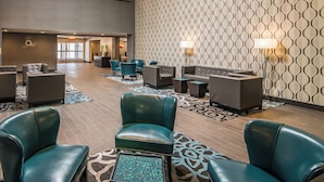 A lobby with teal leather chairs, a patterned wall, and a reception desk. - Elevate Hotel at Sierra Blanca (Ruidoso)