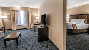 A hotel room with a bed, a desk with a computer, a chair, a small table, and a window with curtains. - Elevate Hotel at Sierra Blanca (Ruidoso)