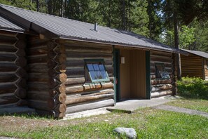 A log cabin with a porch, a window with a view, and a door. - Colter Bay Village (Moran)