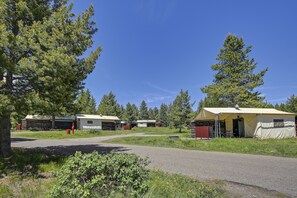 A campground with several cabins and a central tented area, surrounded by trees and a clear sky. - Colter Bay Village (Moran)