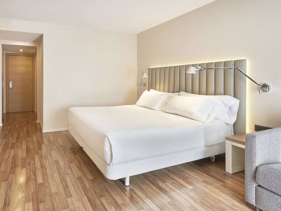 Une chambre d’hôtel avec un lit, un bureau, une chaise et un téléviseur.
