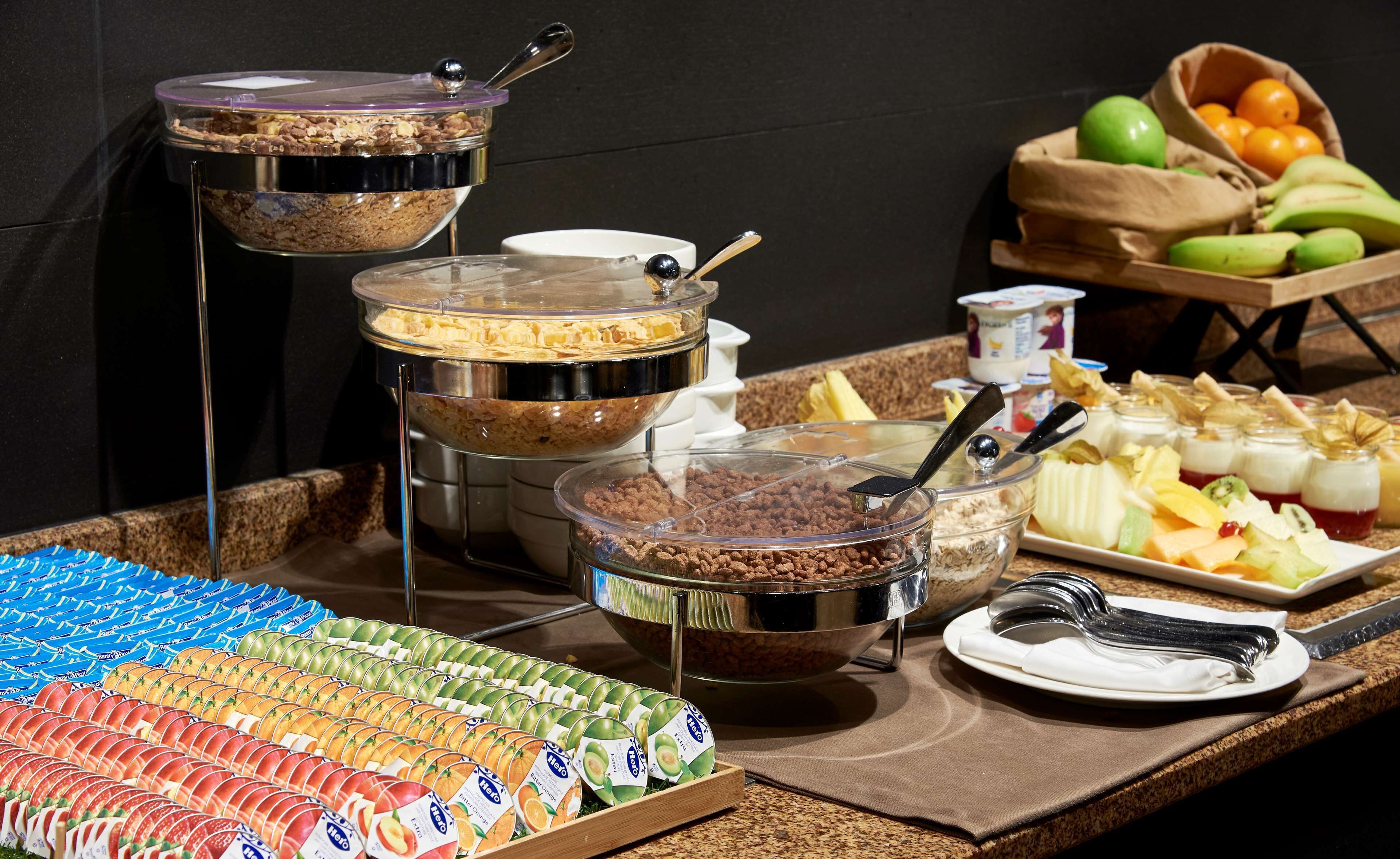 A buffet with various food items, including fruits, yogurt, and cereal.