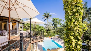 Uma área de piscina com deck de madeira, guarda-sóis e espreguiçadeiras.