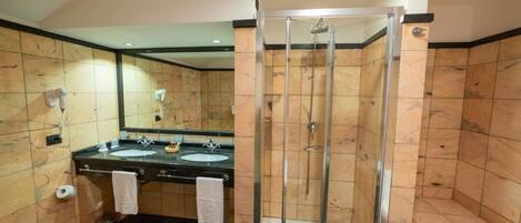 Une salle de bain avec deux lavabos, une douche à parois de verre et une baignoire.