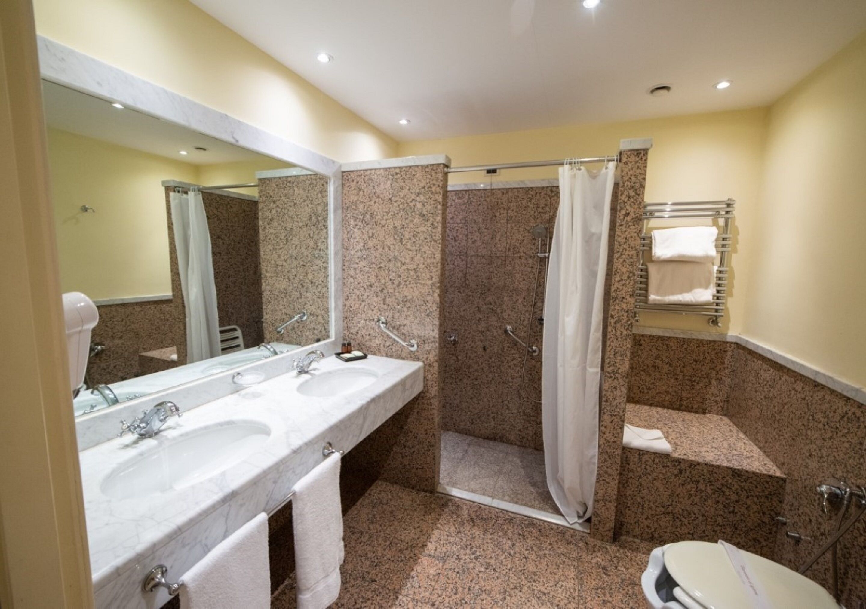 Un bagno con due lavandini, una doccia, un WC e uno specchio.
