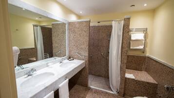 Un bagno con due lavandini, una doccia, un WC e uno specchio.