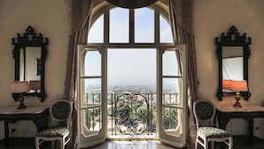 A room with a large window, two chairs, a table, and a mirror. - Villa Tuscolana (Frascati)