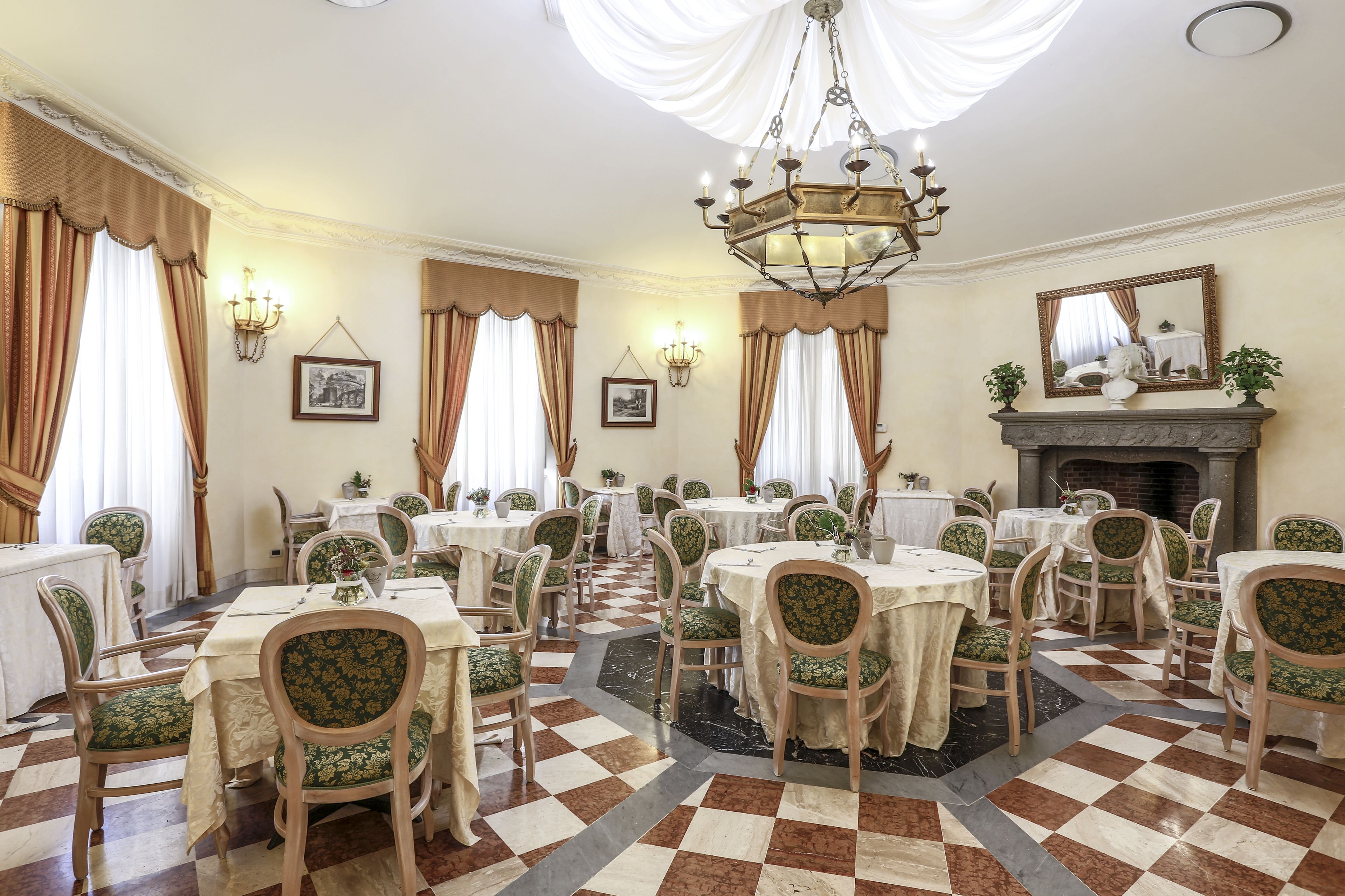Una sala da pranzo con diversi tavoli e sedie, lampadari e quadri appesi alle pareti.