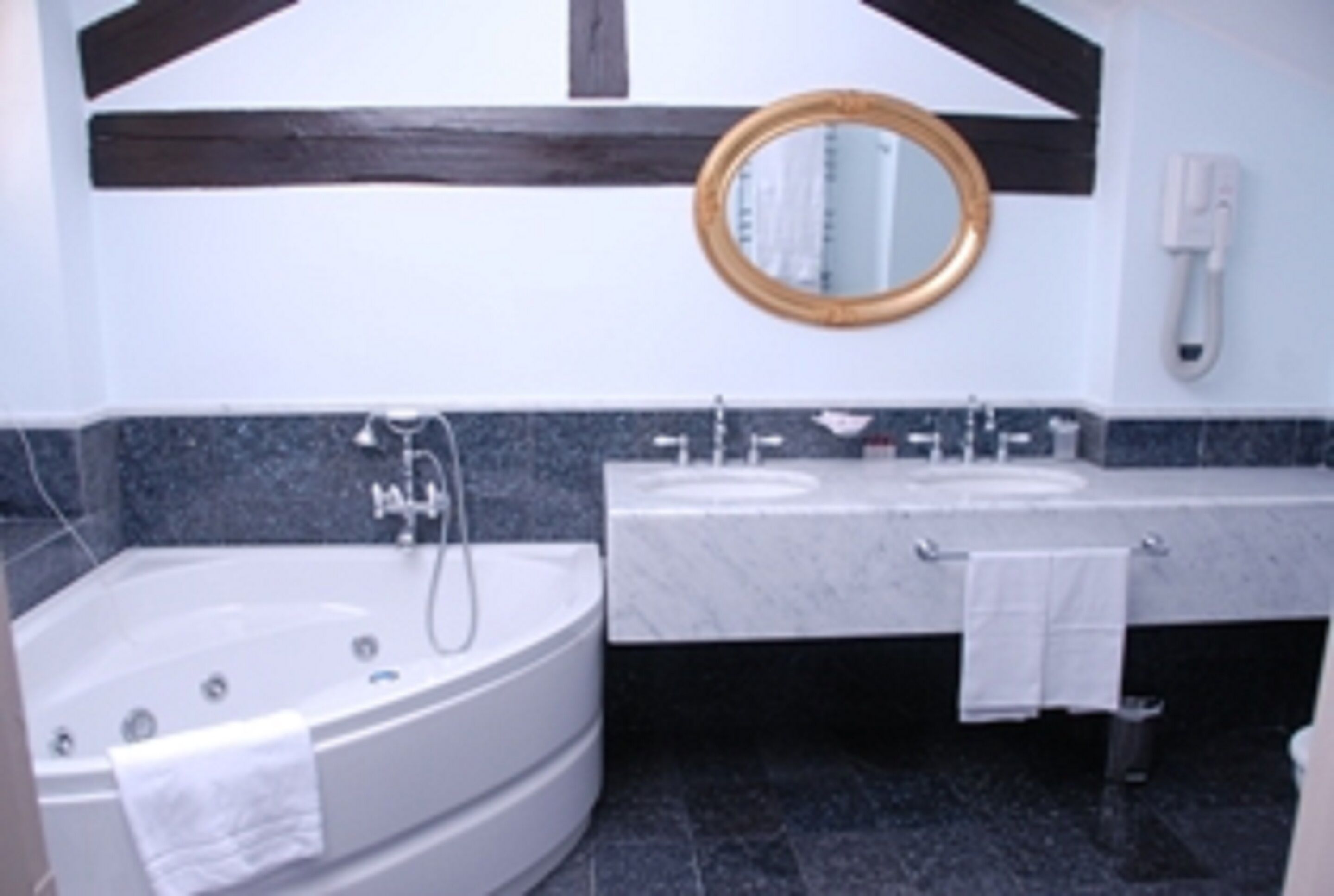 A modern bathroom with a freestanding bathtub, a vanity with two sinks, a mirror, and a telephone.