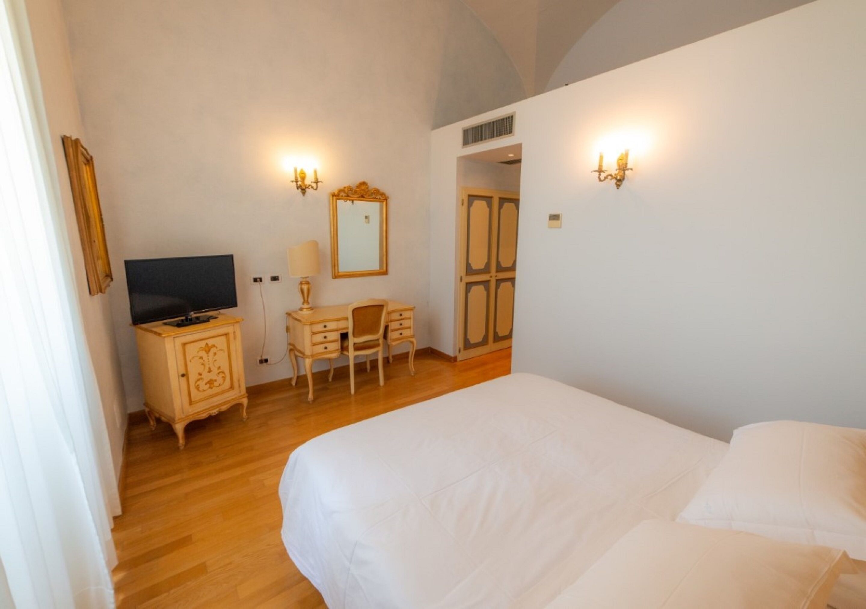 Una camera da letto con un letto, una scrivania, una sedia, una televisione e applique.