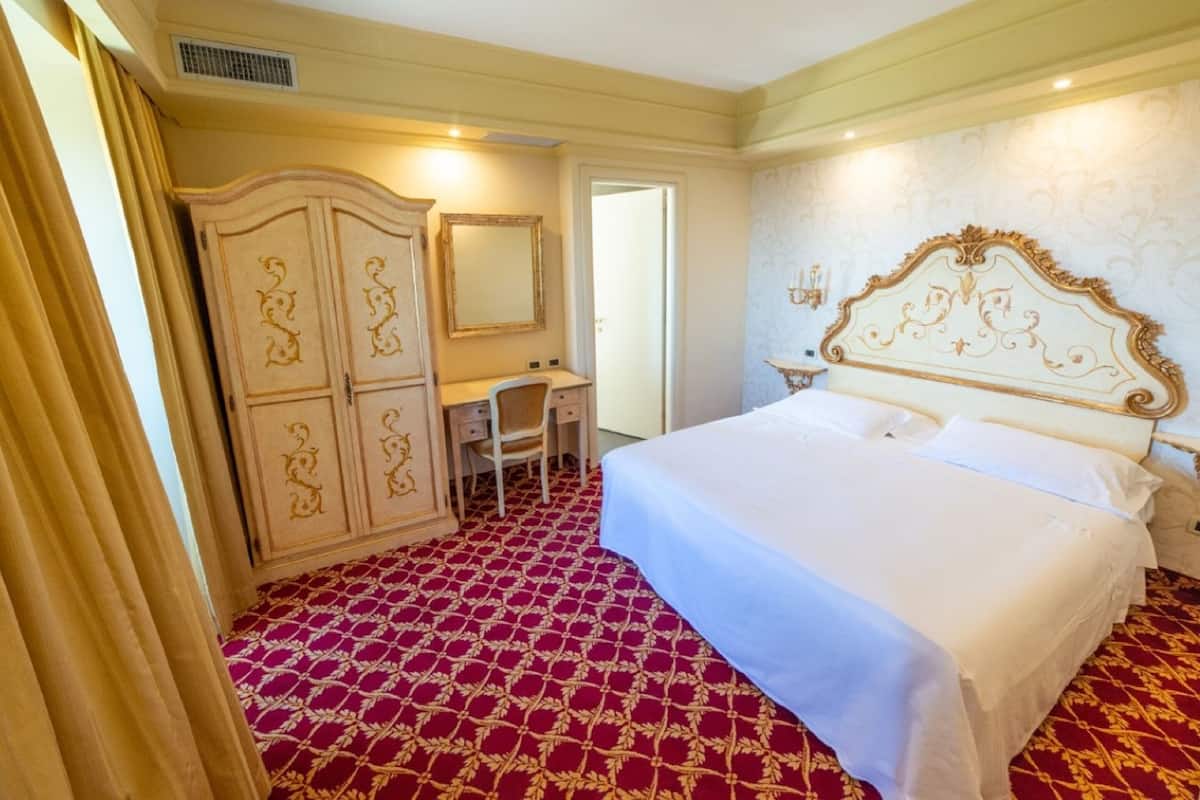 Een hotelkamer met een groot bed, een bureau en een kledingkast.