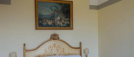 A hotel room with a large bed, a bench, two bedside tables, and a painting on the wall.