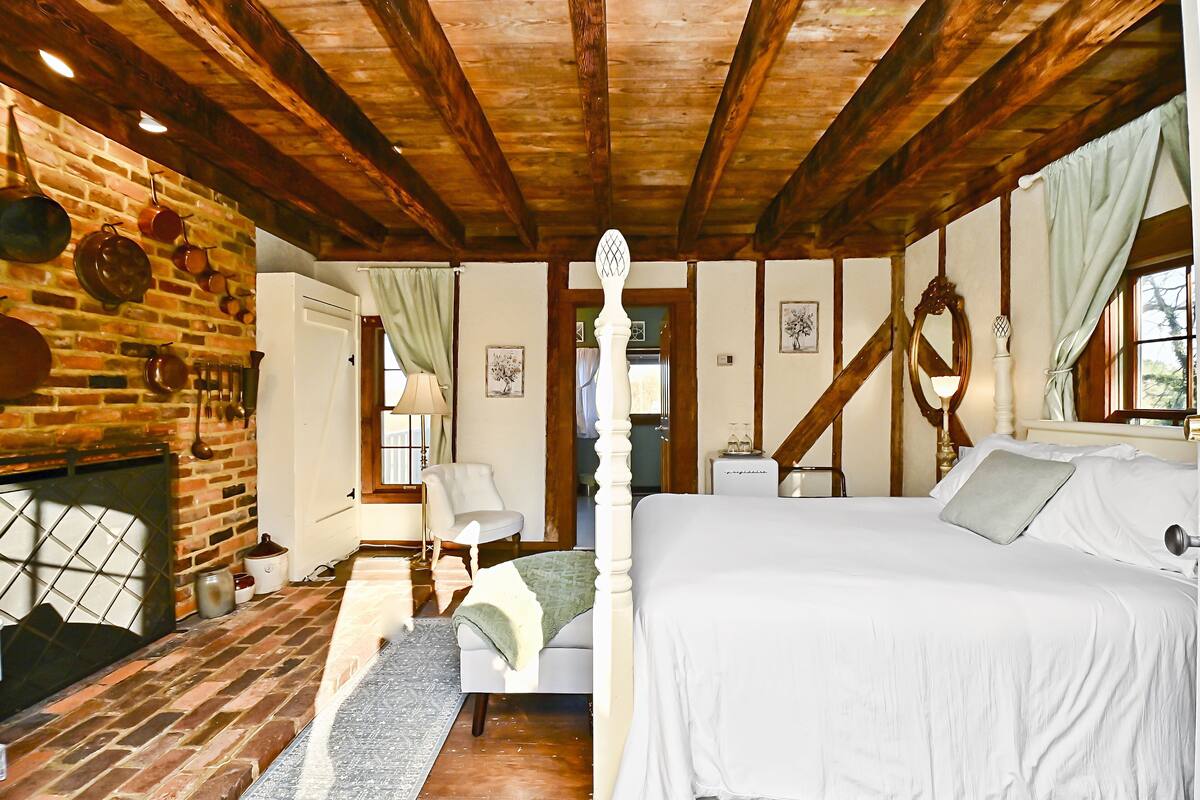 Un dormitorio con una cama con dosel, una chimenea de ladrillo y un techo de madera.