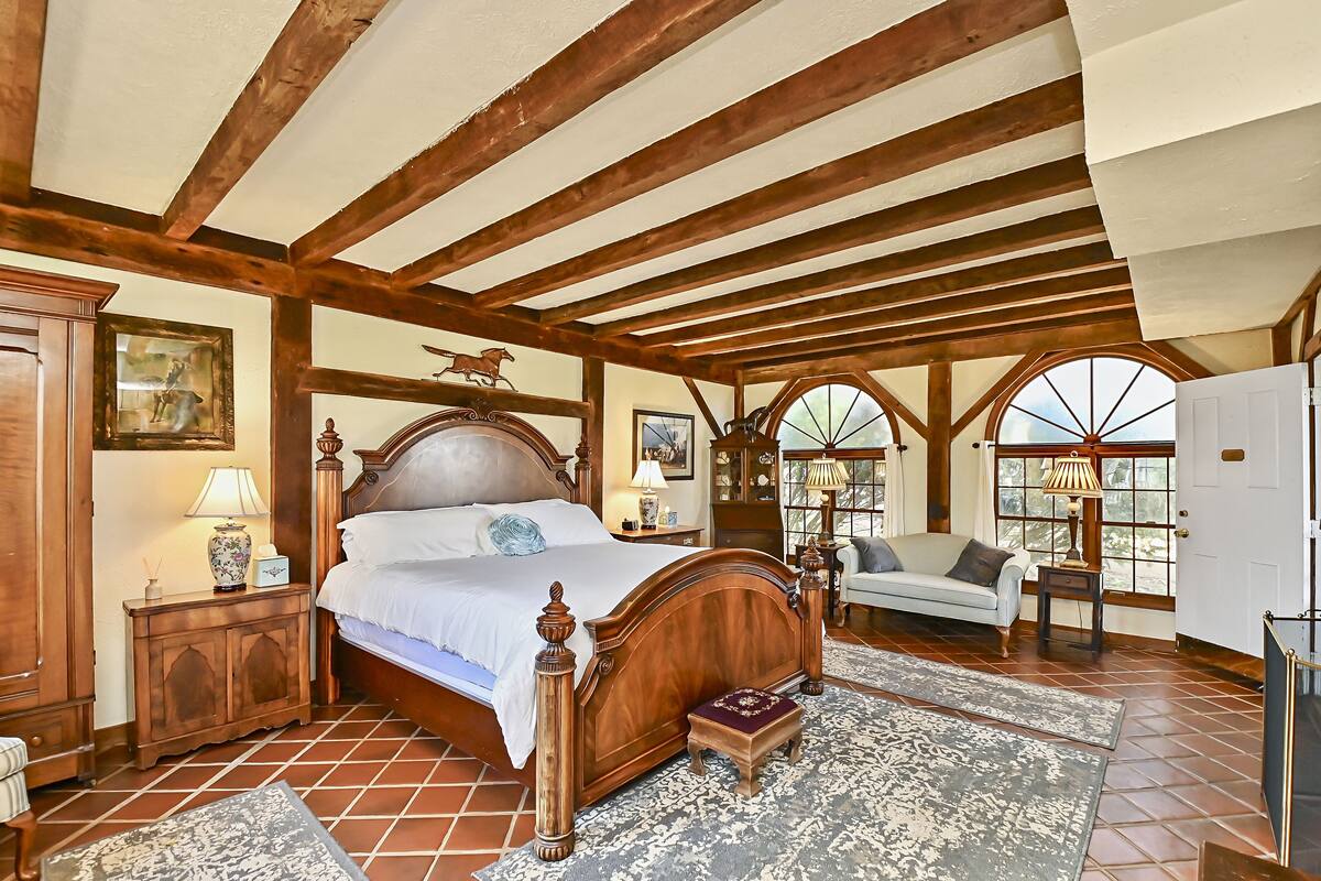 Un dormitorio con una cama de madera, una mesita de noche, un sofá y una ventana con vistas.