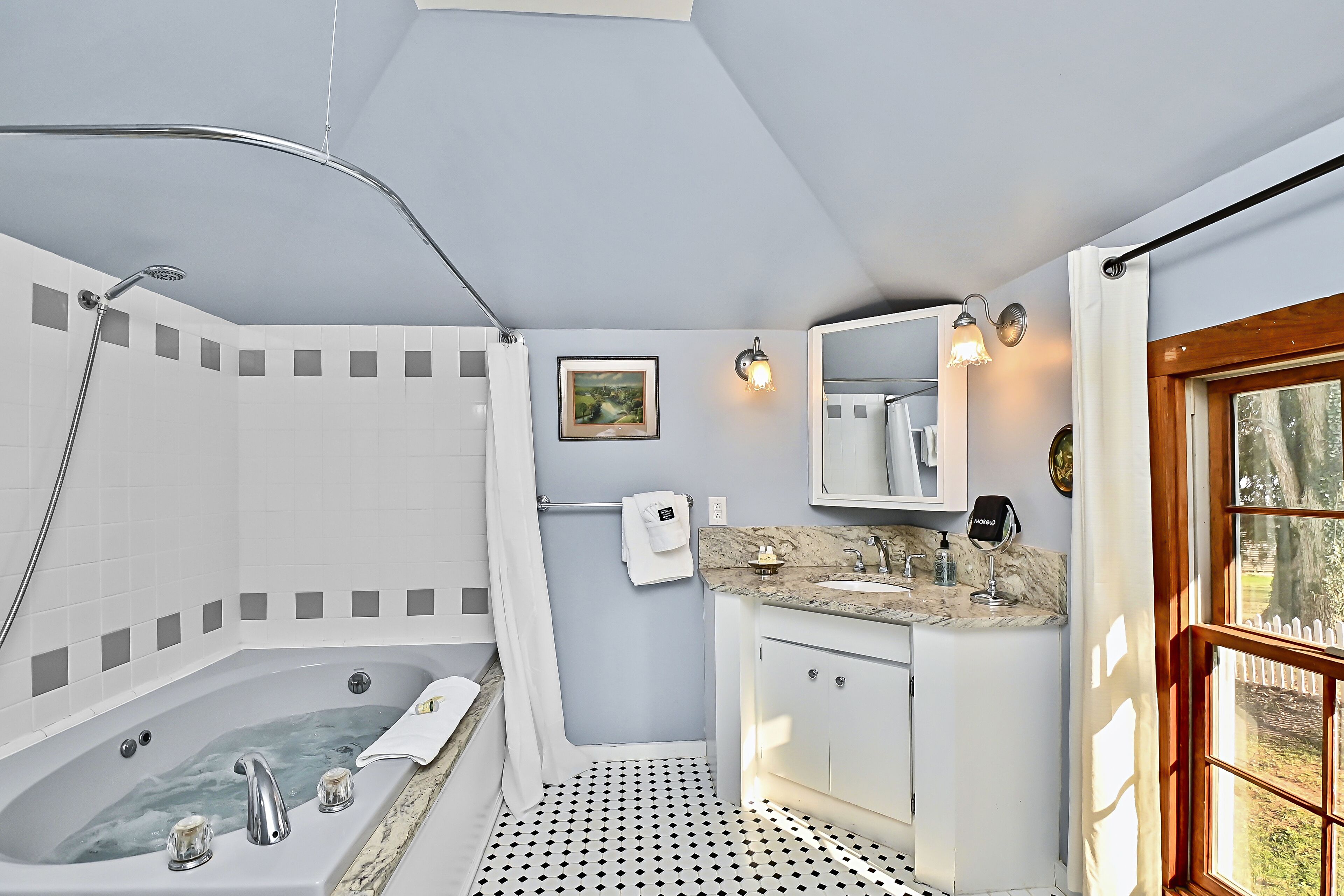 Un baño moderno con una bañera independiente, un tocador con encimera de mármol y un ventanal grande.