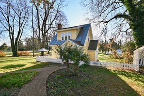 A house with a sloped roof, surrounded by a white picket fence, a small tree, and a pathway leading to the house. - Prospect Hill Inn & Restaurant (Louisa)