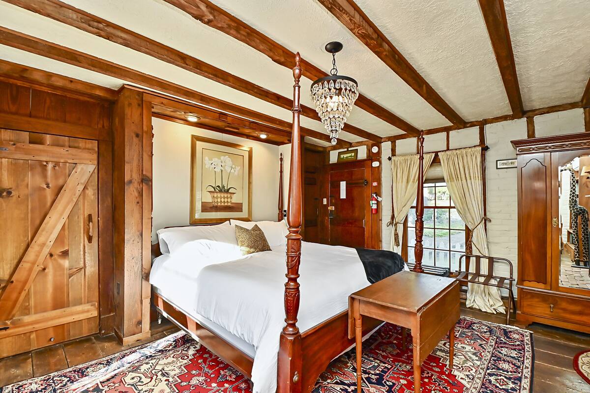 Una cama con dosel, un candelabro, paredes de madera y un espejo grande.