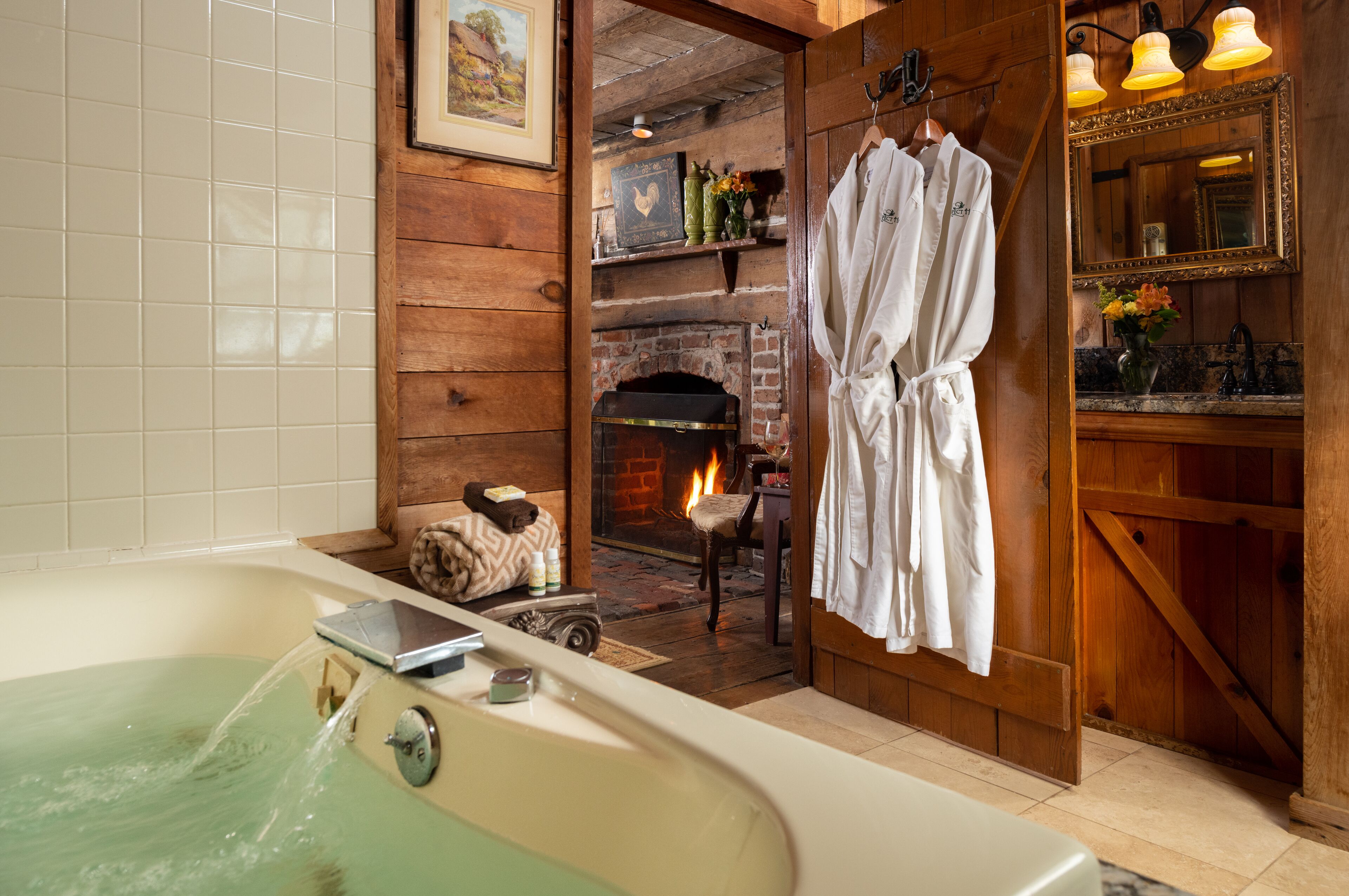 A bathroom with a bathtub, a wooden wall, a fireplace, and a robe hanging on a rack.