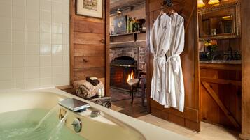 A bathroom with a bathtub, a wooden wall, a fireplace, and a robe hanging on a rack.