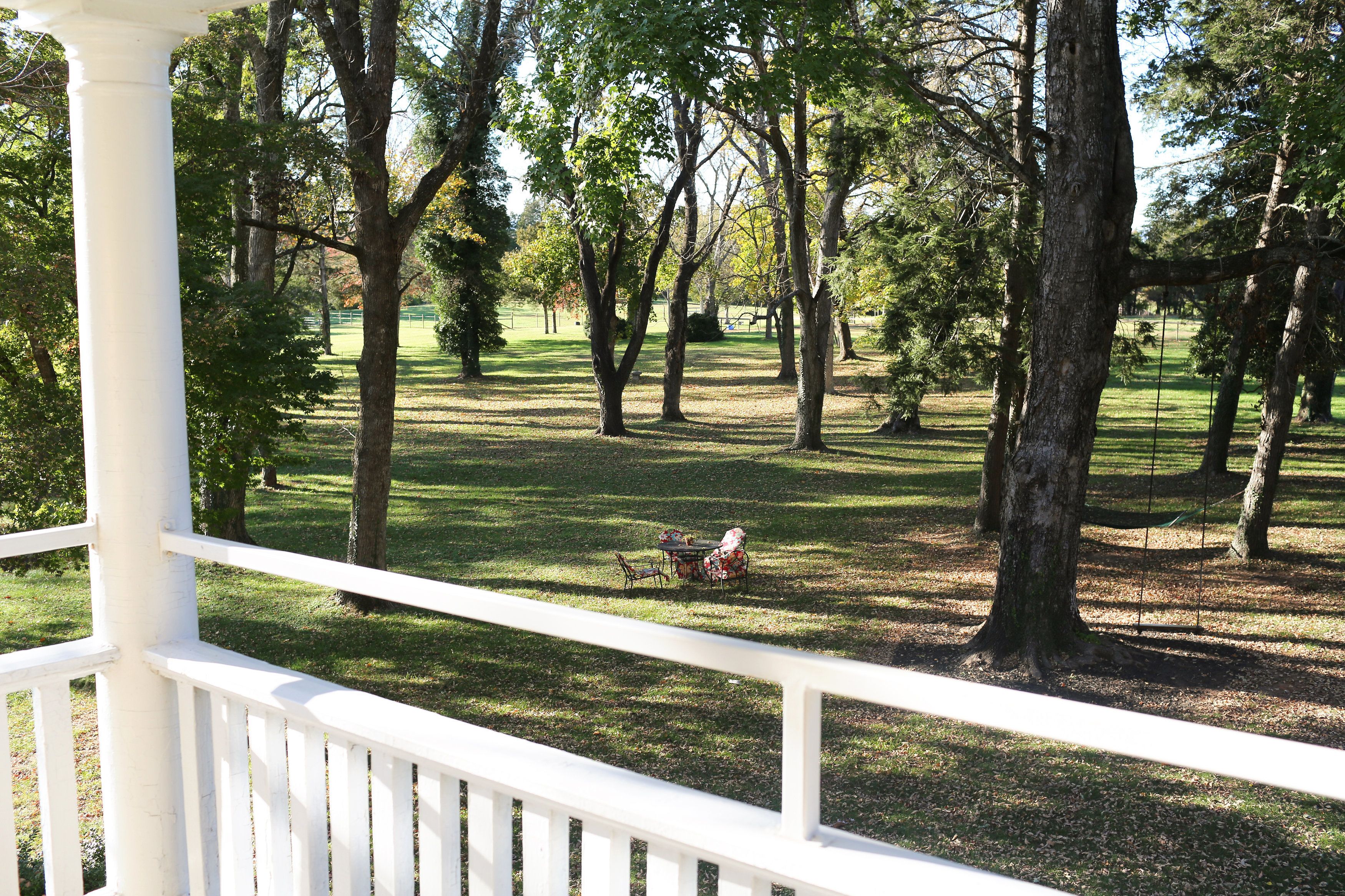A gazebo with a white railing overlooking a grassy area with trees and a picnic table.