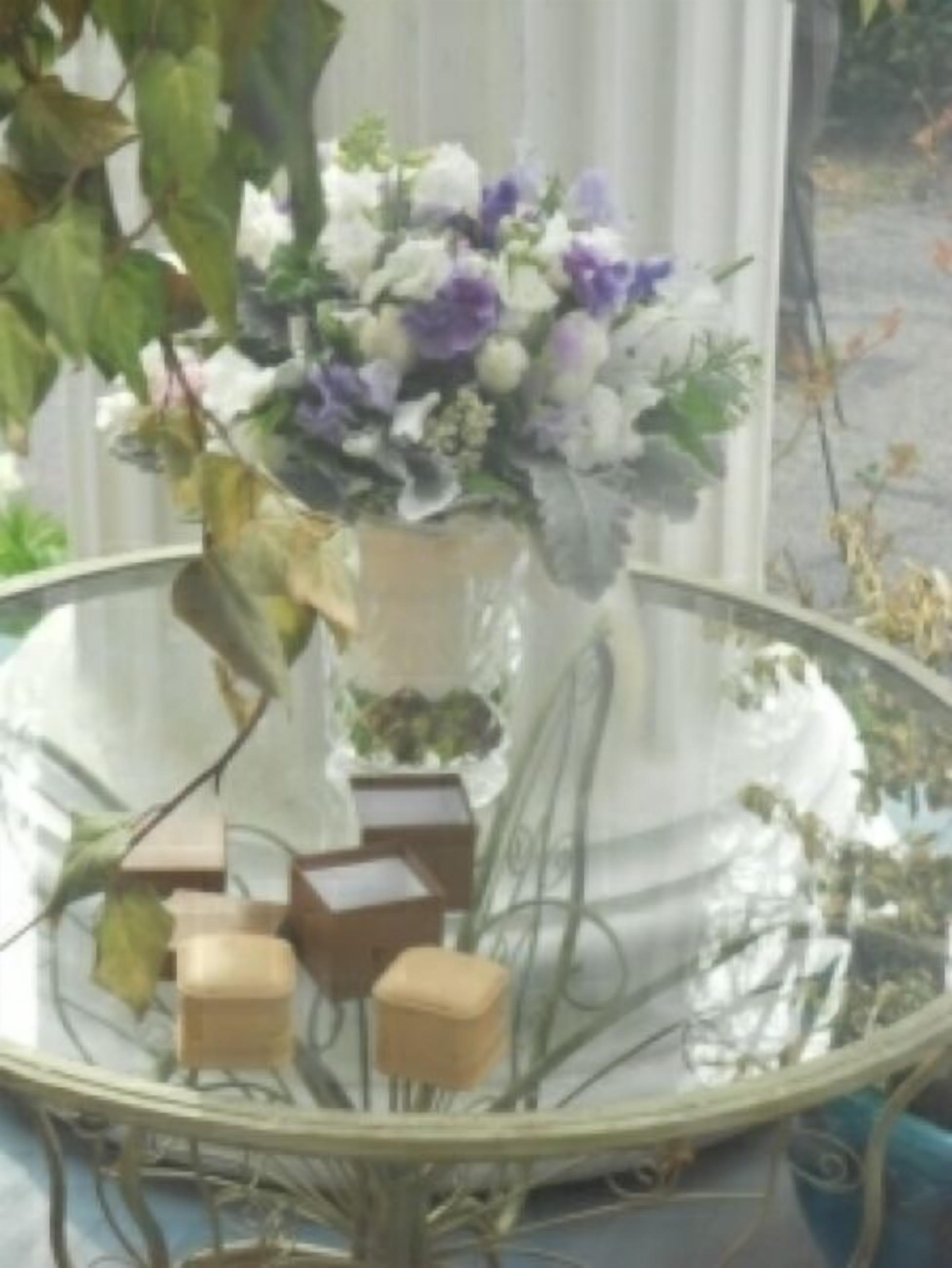 Uma mesa de vidro com um vaso de flores e vários objetos retangulares.