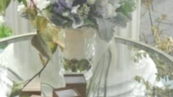 Uma mesa de vidro com um vaso de flores e vários objetos retangulares.