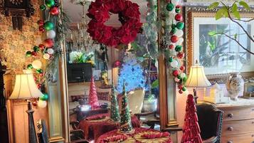 A room with a large mirror, Christmas decorations, a red tablecloth, and a small Christmas tree.