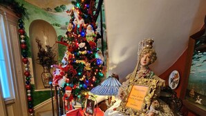 Une pièce décorée d’un sapin de Noël, d’une poupée ancienne et d’une pancarte sur laquelle on peut lire : « Bienvenue au Jardin de la Maison de 1836 ».