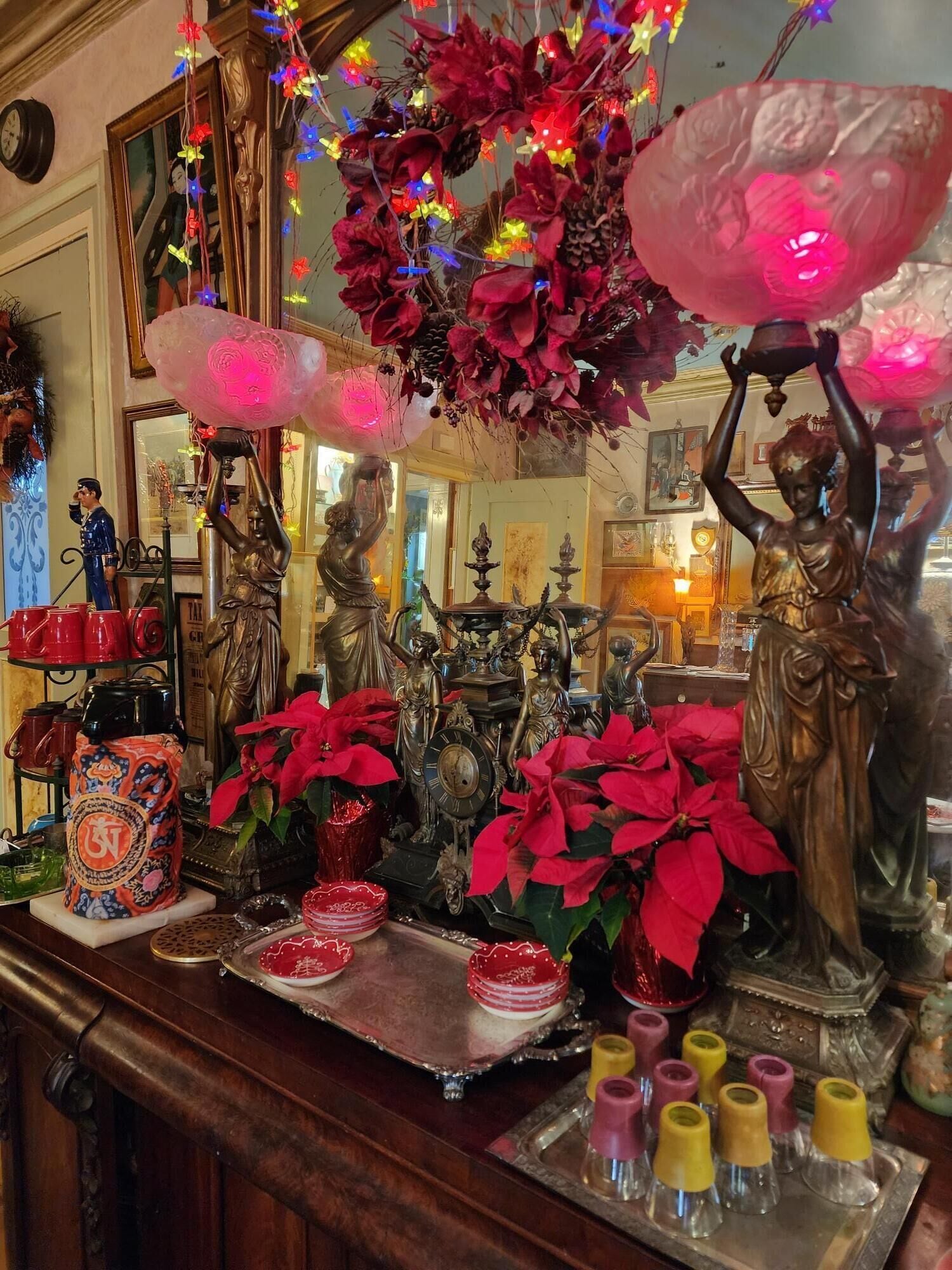 Une pièce dans laquelle se trouve une table en bois, sur laquelle sont disposés divers objets, notamment une horloge, des poinsettias rouges et des statues décoratives.