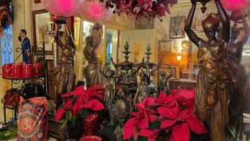 Une pièce dans laquelle se trouve une table en bois, sur laquelle sont disposés divers objets, notamment une horloge, des poinsettias rouges et des statues décoratives.