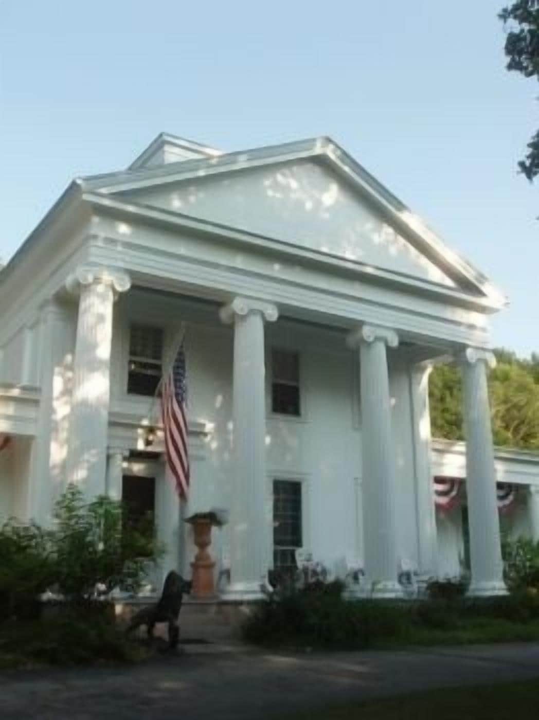 A stately building with a symmetrical facade, large columns, and an American flag.