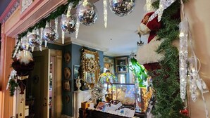Une pièce décorée avec goût, dotée d’un piano, d’éléments de décoration de Noël et d’un miroir.